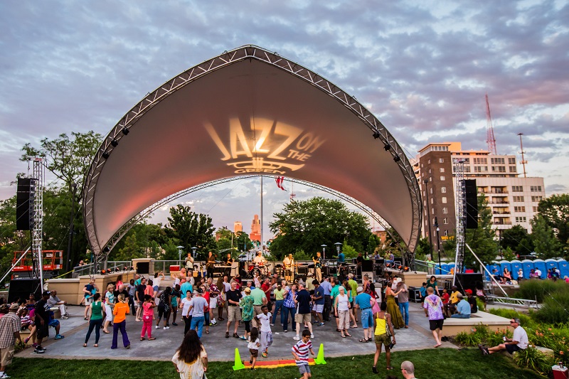 Attendees dance in front of the Jazz on the Green stage and awning 