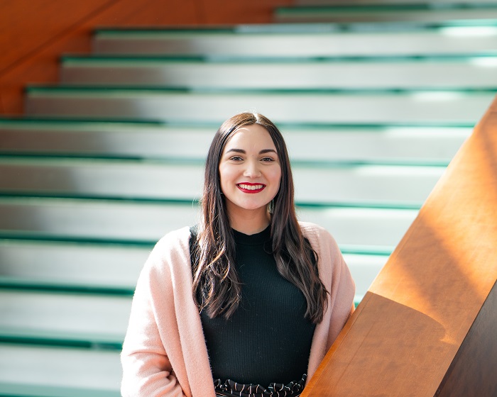 Intern Christina Becker stands at the glass staircase in the Holland Center.