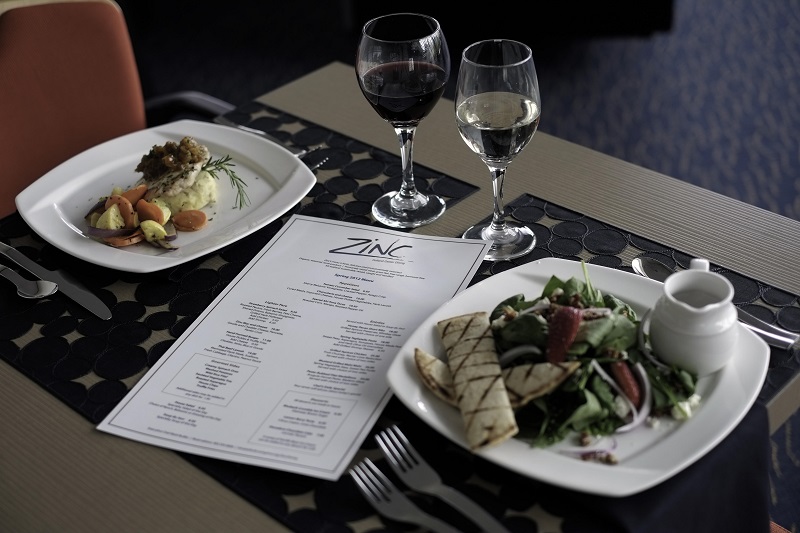 A dinner table is set with two wine glasses and a menu