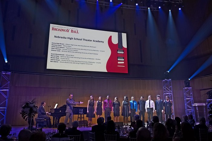 Brian d'Arcy James holds his hands out introducing the NHSTA ensemble on stage at Broadway Ball.