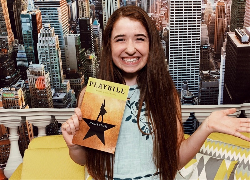 Teen girl smiles while holding HAMILTON playbill