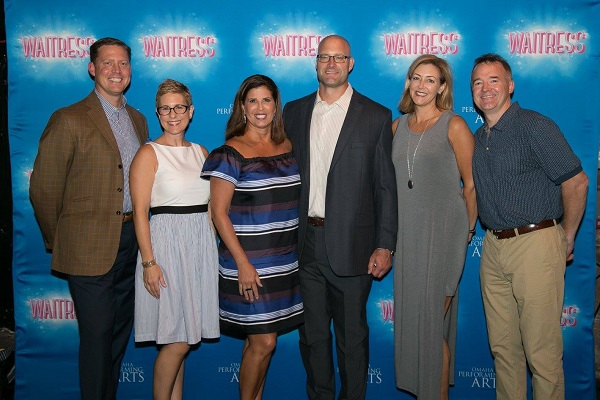 Presenters members in front of the Waitress photobooth backdrop